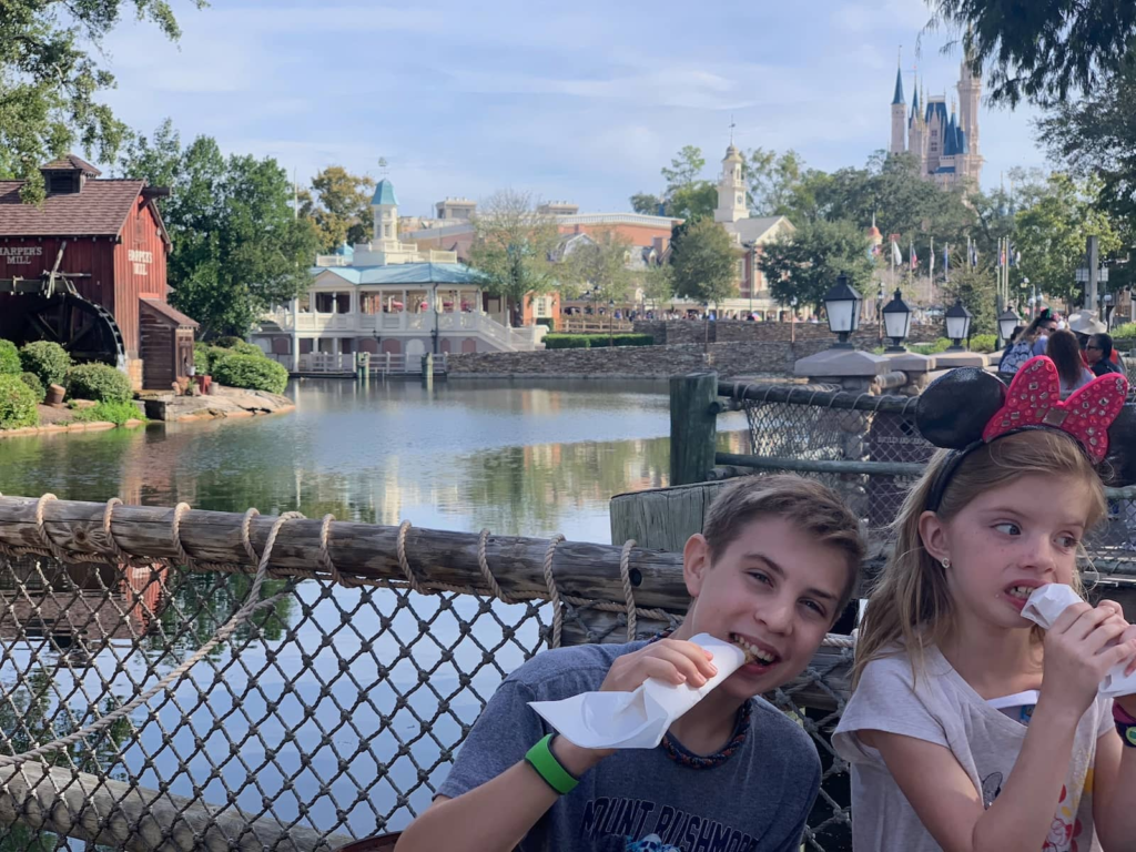 Kids enjoying a snack break during a relaxed Disney World day near Tom Sawyer Island.